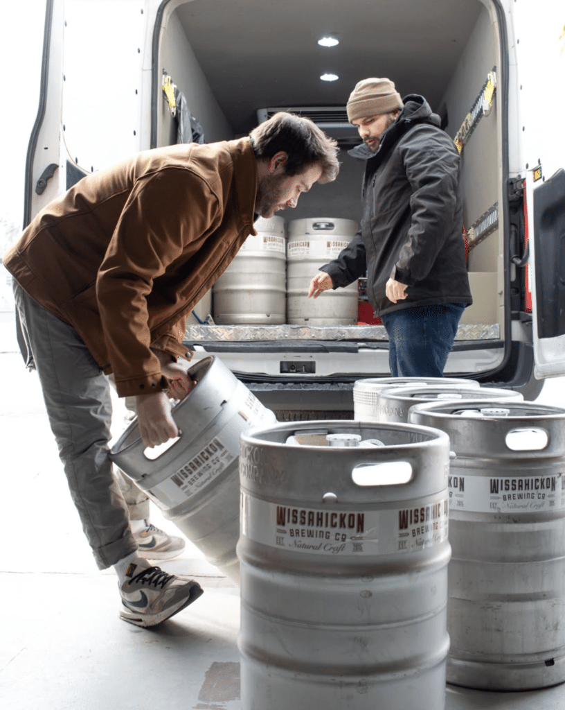 A photo shows two employees of Wissahickon Brewing Company loading a van with kegs of Philadelphia beer in the brewery's East Falls location.
